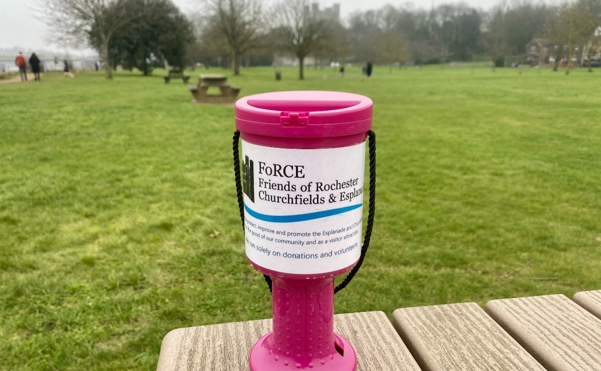 A pink FoRCE donation collection pot on a bench in the Esplanade Gardens