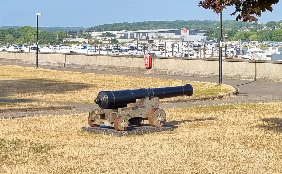 A Georgian cannon sitting amid the grass of the Esplanade Gardens with the river wall in the background