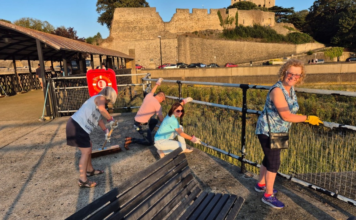FoRCE volunteers scrape old paint from the railings at the end of Rochester Pier