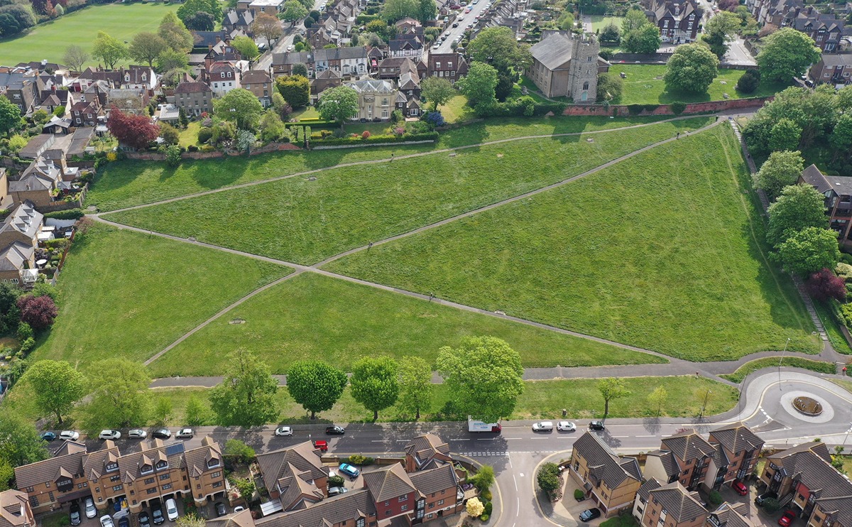 An aerial view of Churchfields, a roughly rectangular area of grass on the steep side of the Medway Valley, crossed by paths and with a church at the top