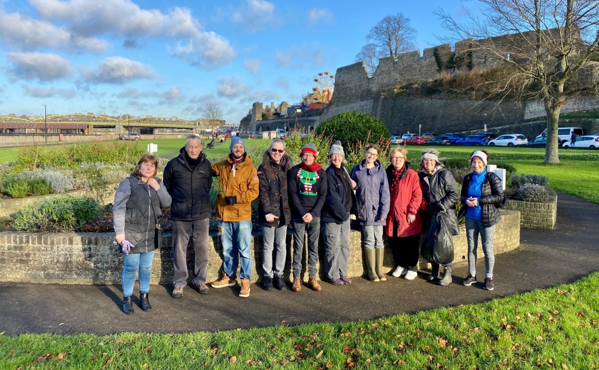 A group of our volunteers stand together in front of the Suffrage Sensory Garden beds