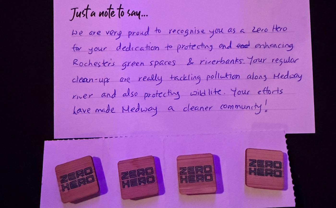 A handwritten note and four "Zero Hero" badges