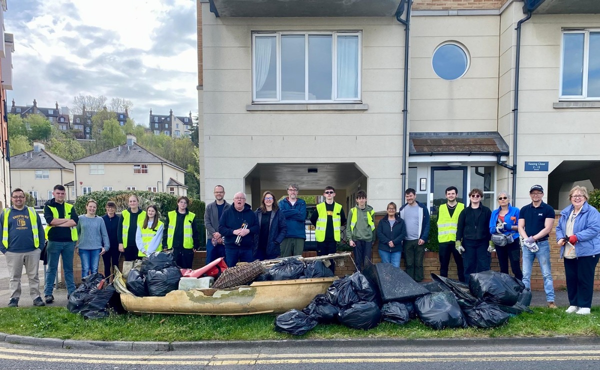 Volunteers pose for a group photo with many sacks of collected litter and some larger items, including an abandoned dinghy!