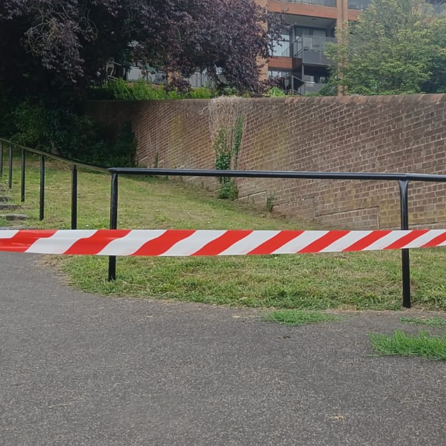 Railings freshly painted in smart black paint, roped off with hazard tape until it's dry