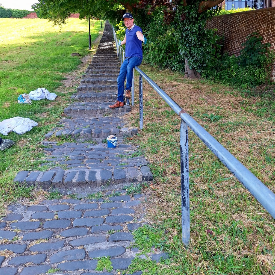 One of our volunteers poses with the railings alongisde some ascending steps in Churchfields before they are painted.
